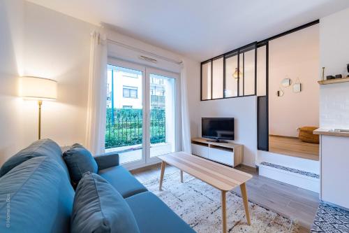 un salon avec un canapé bleu et une table dans l'établissement Woody Cocon by Plaza - Proche Disneyland Paris, à Montévrain