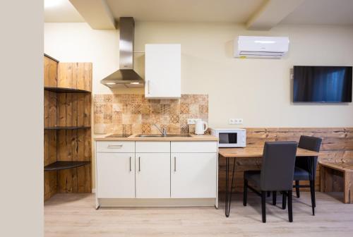 eine Küche mit weißen Schränken und einem Tisch mit Stühlen in der Unterkunft Gästehaus - Boardinghouse Magnetsried in Seeshaupt