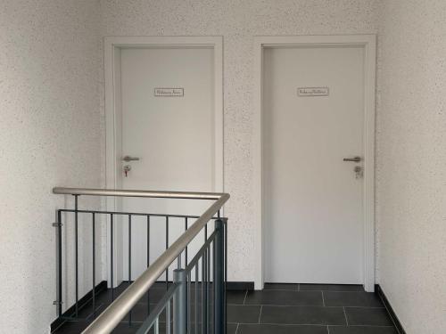 2 puertas blancas en un edificio con escalera en Ferienwohnungen Molkerei Ditzum 45242 en Ditzum