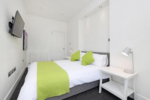 Un dormitorio con una cama verde y blanca y un escritorio en One bed apartment in the heart of Innerleithen, en Innerleithen