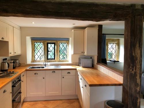 a kitchen with white cabinets and wooden counter tops at Cotswold Retreat in Great Tew