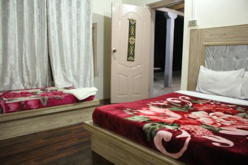 a bedroom with two beds with red sheets and a door at Baltit Heritage Inn in Hunza Valley