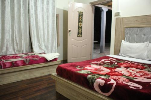 1 Schlafzimmer mit 2 Betten mit roter Bettwäsche und einer Tür in der Unterkunft Baltit Heritage Inn in Hunza