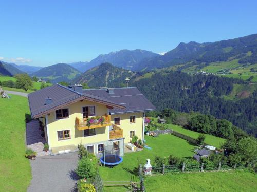 a house on a hill with mountains in the background at Cosy holiday flat in a farmhouse in Taxenbach