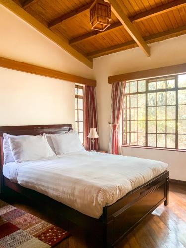 una camera con un grande letto e due finestre di Oilepo Cottage a Naivasha