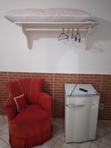 a red chair sitting next to a trash can at Pousada Clave de Sol in Conservatória