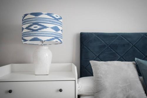 a lamp on a night stand next to a bed at Apartamento en Centro Histórico con patio Romano in San Lorenzo de El Escorial