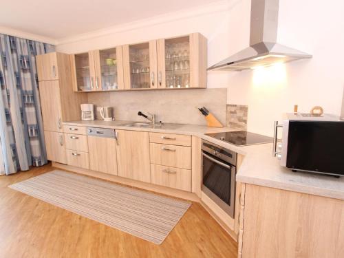 a kitchen with wooden cabinets and a sink and a microwave at Apartment in Bad Hofgastein with sauna in Bad Hofgastein