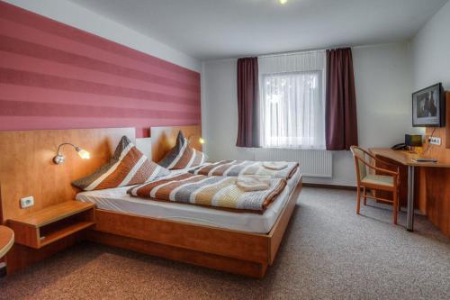 a hotel room with a bed and a desk and a desk at Landhotel & Brauhaus Prignitzer Hof in Pritzwalk