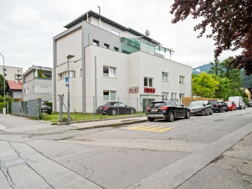 Un edificio blanco con coches aparcados en un estacionamiento. en Apartment Innsbruck near Bergisel Ski Jump, en Innsbruck