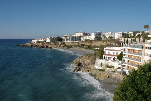 a view of a beach with buildings and the ocean at Hostal Azahara in Nerja