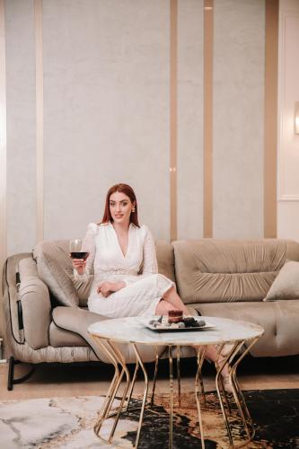 a woman sitting on a couch holding a glass of wine at Sky Hotel Korce in Korçë