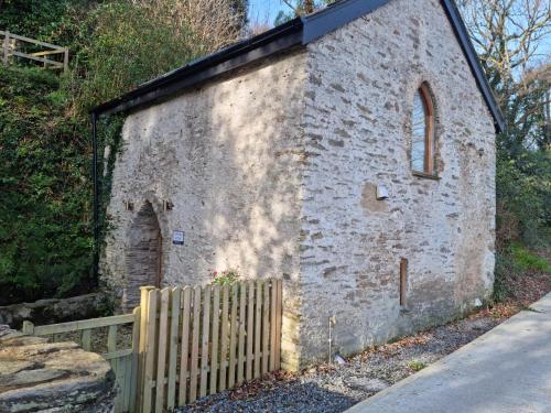 an old brick building with a fence next to it at The Well house in Ilfracombe
