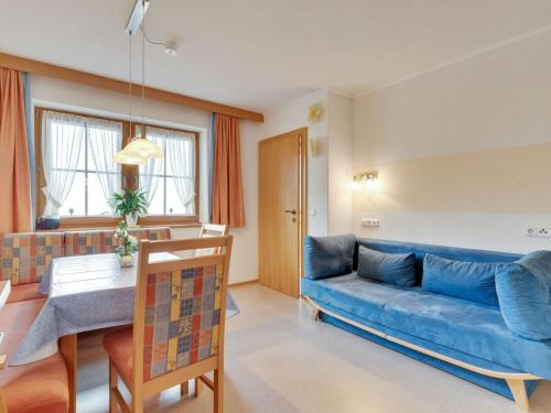 un soggiorno con divano blu e tavolo di Quaint Apartment in Hainzenberg near Horbergbahn a Hainzenberg