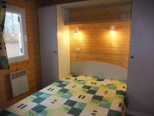 een slaapkamer met een bed met een geruite deken bij Chalet Campanules 36 in Mélisey