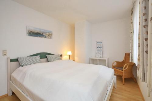 ein weißes Schlafzimmer mit einem weißen Bett und einem Stuhl in der Unterkunft Waterkant Wohnung 19 - Klabautermann in Boltenhagen