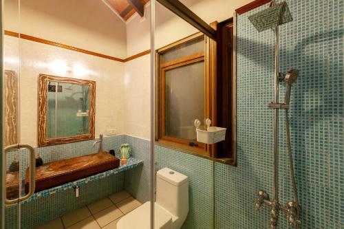 a bathroom with a toilet and a glass shower at Aranyam Villa by StayVista with Modern wooden interiors, Kidszone, Indoor games & plunge pool in Lonavala