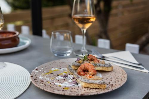 a plate of food on a table with a glass of wine at Meliores Rooms in Šilo