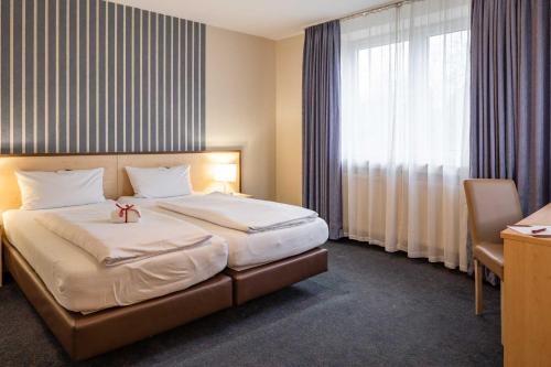 a hotel room with a bed and a window at Hotel Astoria City Resort in Essen