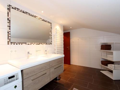 ein Badezimmer mit einem Waschbecken und einem großen Spiegel in der Unterkunft Spacious Chalet near Ski area in Itter in Itter