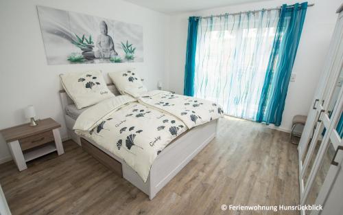a bedroom with a bed and a window with blue curtains at Ferienwohnung / Haus Hunsrückblick in Hochstetten-Dhaun