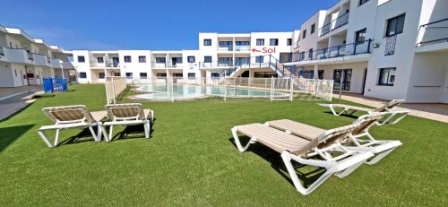 two chairs and a bench on a lawn in front of a building at Ferienwohnung SOL - Costa Calma - WiFi - Pool - max 4 Personen in Costa Calma