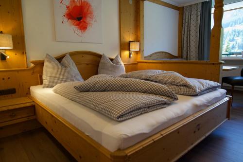 een slaapkamer met een houten bed met kussens erop bij Garni Hotel Wildanger in Zöblen