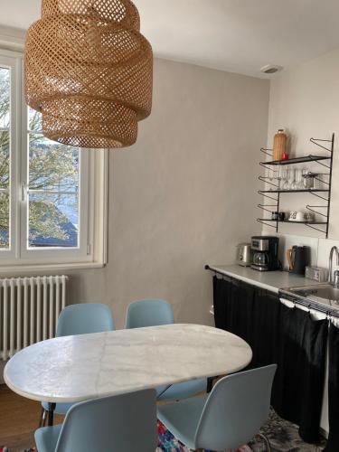 une cuisine avec une table blanche et des chaises bleues dans l'établissement La suite & Caux 2, à Cany-Barville