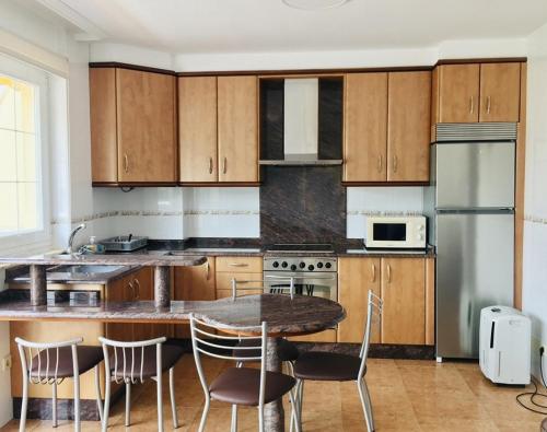 eine Küche mit Holzschränken sowie einem Tisch und Stühlen in der Unterkunft Apartamento Praia de Quenxe in Corcubión