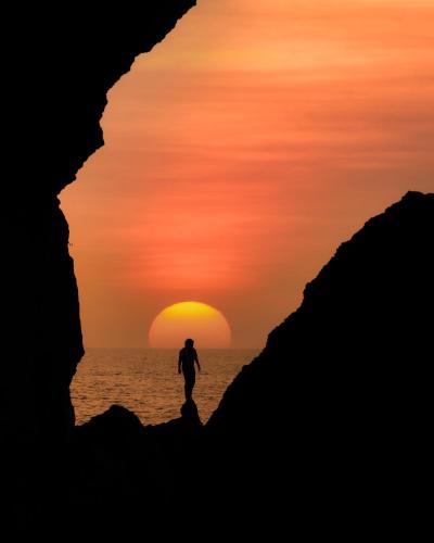 a man walking on the beach at sunset at Fort Tiracol Goa in Arambol