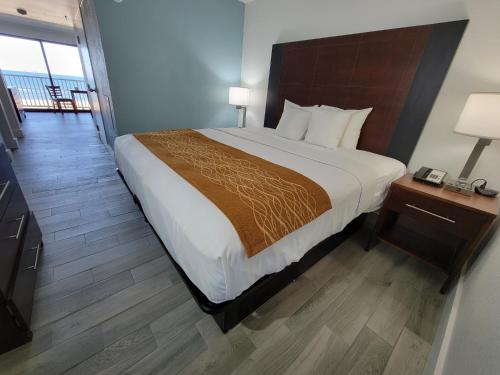 a bedroom with a large bed with a wooden headboard at Coastal Hotel & Suites Virginia Beach - Oceanfront in Virginia Beach