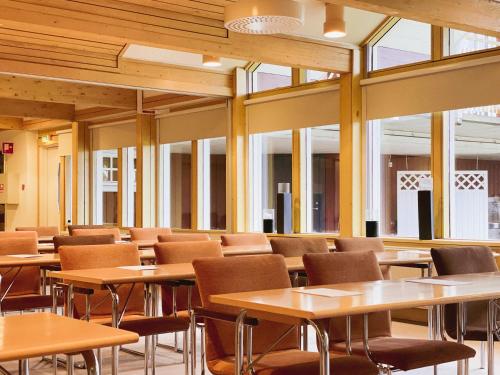 a cafeteria with tables and chairs and windows at Hotell Gyllene Hornet in Tällberg