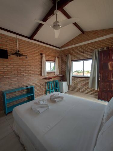 a bedroom with a large white bed and a brick wall at Vila Beija-flor in Canoa Quebrada