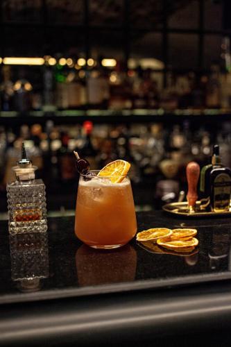 a drink sitting on a bar with an orange slice at Hôtel Roi de Sicile - Rivoli in Paris