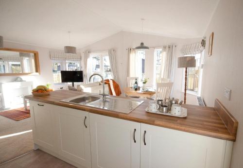a kitchen with white cabinets and a wooden counter top at Hollicarrs - Bumblebee Lodge in York
