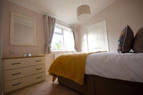 a bedroom with a bed and a dresser and a window at Hollicarrs - Bumblebee Lodge in York