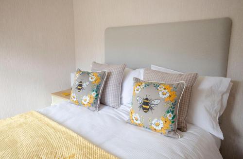 a bed with four pillows with butterflies on it at Hollicarrs - Bumblebee Lodge in York