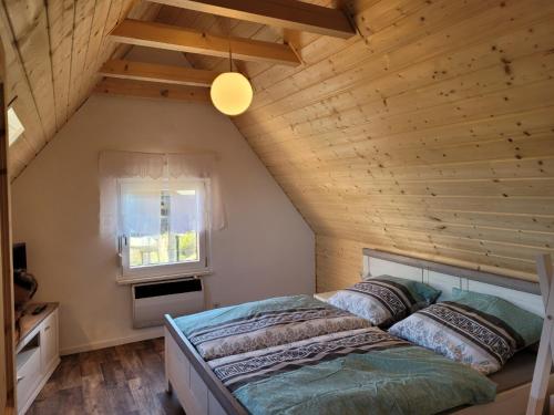 Cama en habitación con techo de madera en Ferienhaus Unstrutblick en Memleben