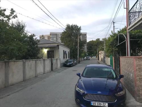 a blue car parked on the side of a street at Wooden Museum in Kutaisi