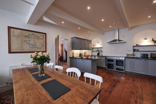 Una gran cocina con una mesa y sillas de madera. en The Cottage Laugharne, en Laugharne