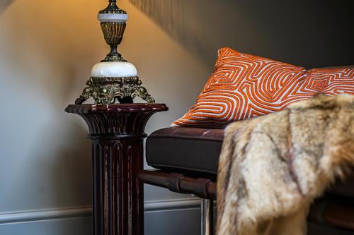 a lamp sitting next to a couch with a pillow at BOHOTEL in Macclesfield