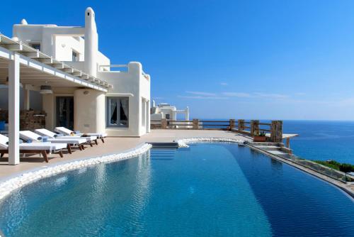 a swimming pool in front of a house with the ocean at Naxos Rock Villas in Stelida