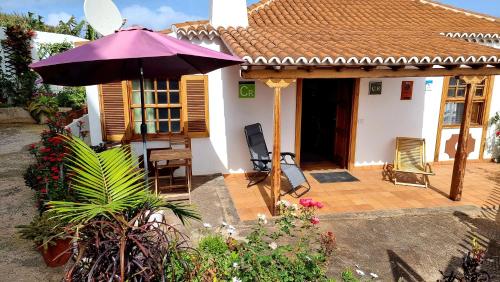 a house with a purple umbrella and a patio at Manos de Oro in Los Sauces