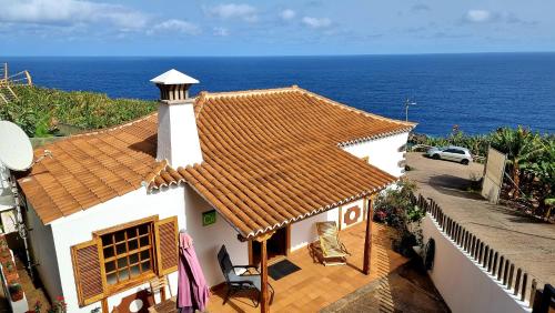 a white house with a brown roof and the ocean at Manos de Oro in Los Sauces