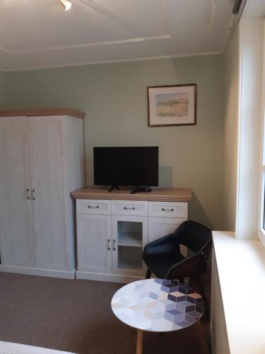 a room with a tv and a chair and a table at Lana in Nida