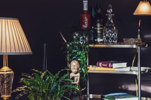 uma mesa com um candeeiro, uma planta e uma prateleira com garrafas em BOHOTEL em Macclesfield