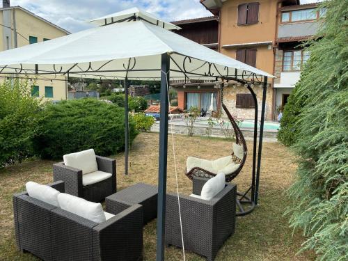 a hammock and chairs under a white umbrella at Nidi del faggio rosso - Family Holiday Home in Maresca