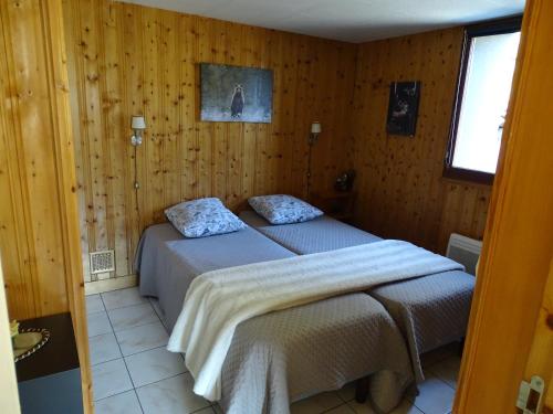two beds in a room with wooden walls at Profiter du calme de la montagne vosgienne in Saulxures-sur-Moselotte