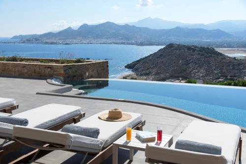 a pool with chairs and a view of the water at Naxos Rock Villas in Stelida