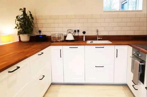 a kitchen with white cabinets and a sink at The Studio a super cute place nr Southwold in Southwold